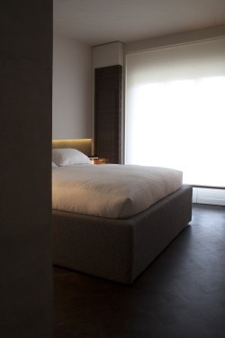 Giolitti is a minimalist house located in Turin, Italy, designed by Fabio Fantolino. The living room features two wooden bookshelf columns that span from the floor to the ceiling. The mixed concrete floors are accented with light grey and wooden furniture. The kitchen and bathrooms utilize natural-toned materials juxtaposed against wooden cabinetry. (14)